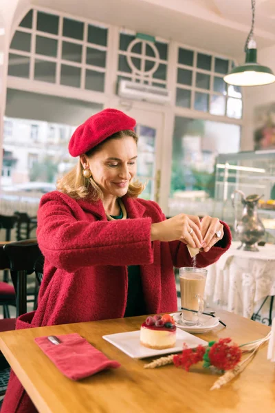 Dessert and coffee. Elegant French woman sitting in nice atmospheric bakery having dessert and coffee