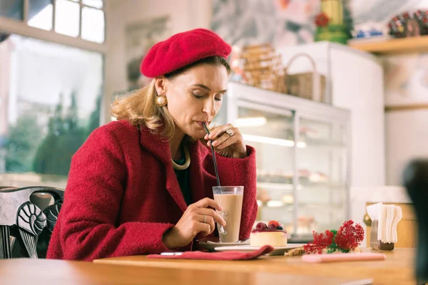 Güzel fırında oturan latte içmek kırmızı giysilerini giyen kadın Fransız — Stok fotoğraf