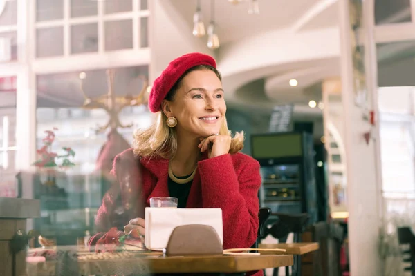 Elegant woman feeling amazing sitting in bakery and looking into window