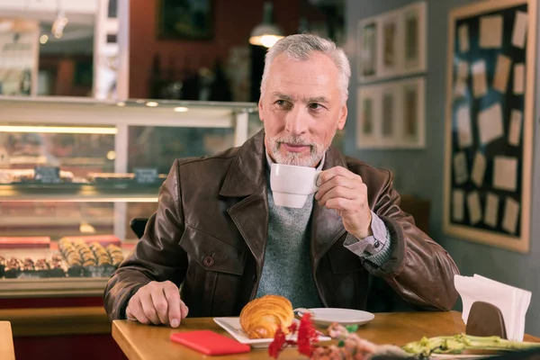 Olgun adam taze kruvasan ve kahve kokusu tadını sakallı — Stok fotoğraf