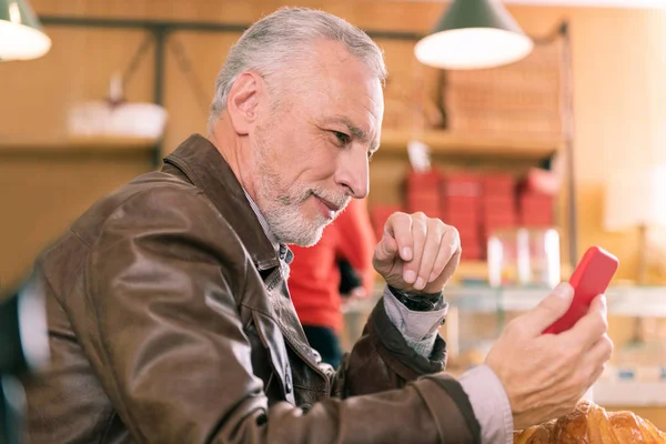 Sakallı gri saçlı Olgun adam onun kırmızı smartphone holding — Stok fotoğraf