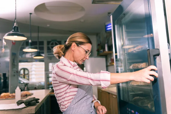 Proprietário da padaria francesa usando óculos olhando para geladeira com sobremesas — Fotografia de Stock