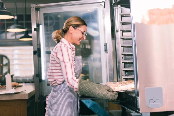 Trabajador radiante de horno de apertura de panadería y sacando bandeja con pastel — Foto de Stock