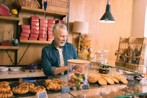 Brodaty siwy właściciela piekarni sprzedaży ciasteczek rano — Zdjęcie stockowe