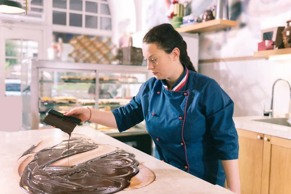 Dark-haired female chef feeling inspired cooking tempered chocolate