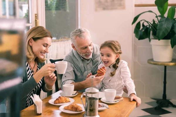 Ler gråhåriga farfar ger croissant sin lilla flicka — Stockfoto