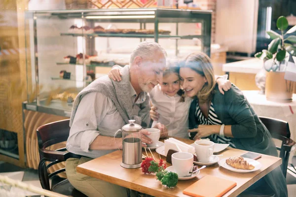 Kärleksfull barnbarn bär vit skjorta kramar hennes morföräldrar — Stockfoto