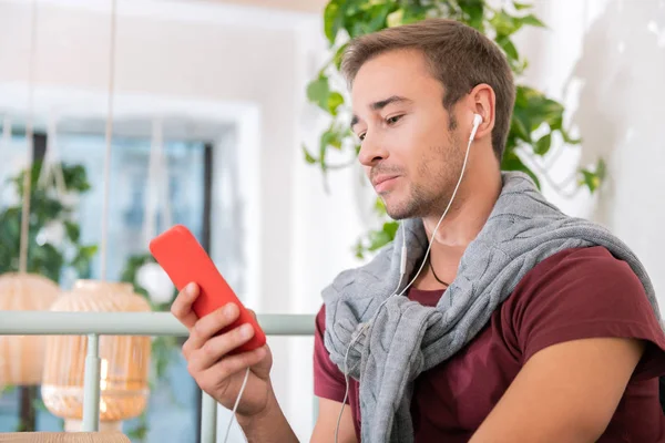 Bonito homem ouvindo música usando seu telefone e fones de ouvido — Fotografia de Stock