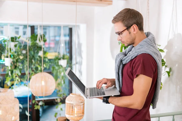 Freelancer con gafas sujetando laptop trabajando todo el día en coworking —  Fotos de Stock
