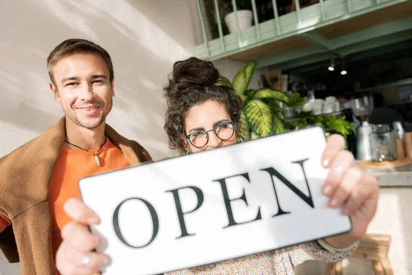 Frau mit Brille mit offenem Schild eröffnet Café mit Ehemann — Stockfoto