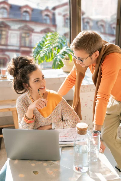Woman sitting in front of laptop asking some advice of her man — Stock Photo, Image