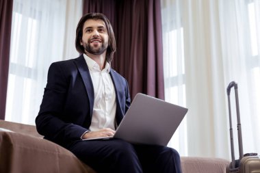 Neşeli akıllı yakışıklı girişimci yatağa oturmuş