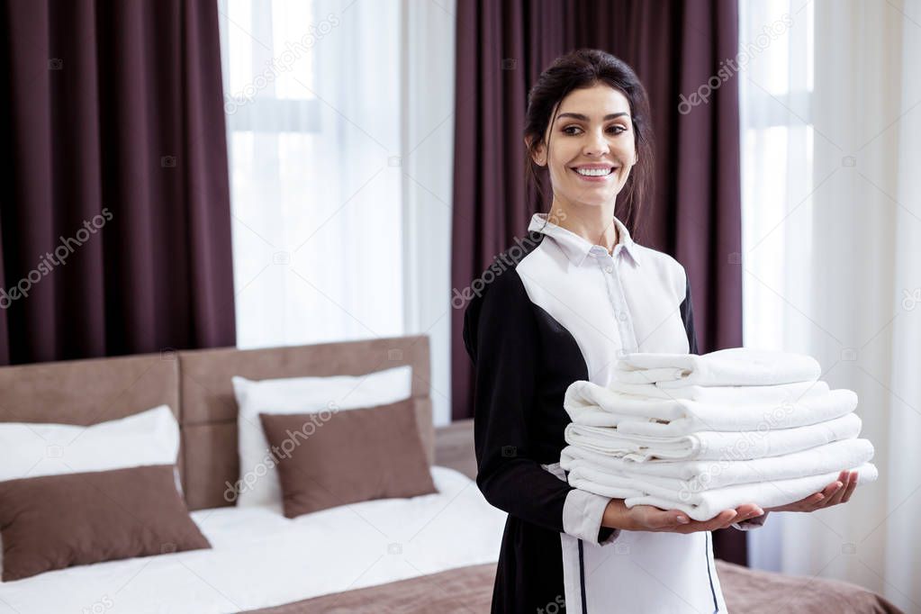 Positive young woman bringing fresh white towels