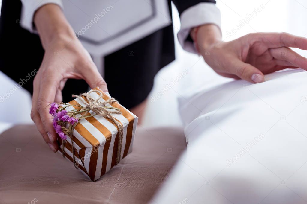 Close up of a gift box being put on the bed
