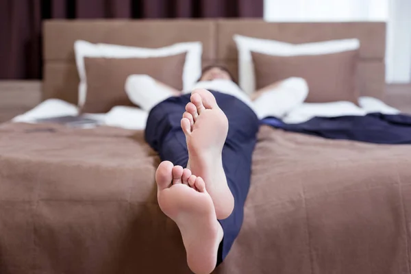 Pies de un buen hombre de negocios cansado descansando en la cama — Foto de Stock