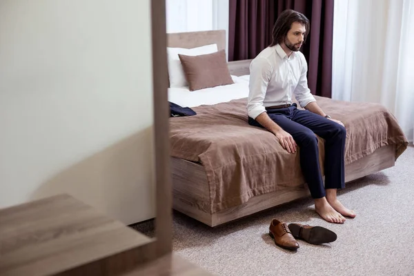 Pria yang lelah duduk di tempat tidur di hotel — Stok Foto