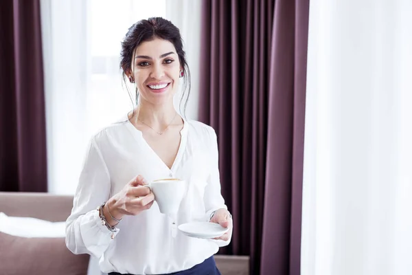 Mujer atractiva alegre sosteniendo una taza con café — Foto de Stock