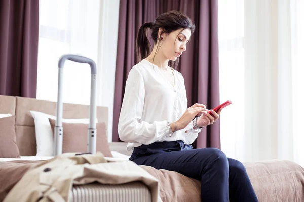 Sérieuse jeune femme assise sur le lit de l'hôtel — Photo