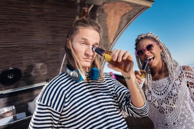 Kadın sandalyede Nehri yakınında oturan ve bira içme dreadlocks ile