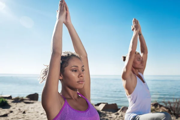 Close up curly appealing woman wearing purple sport shirt doing yoga — Stock Photo, Image