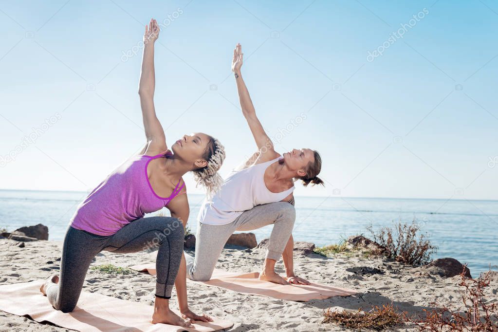 Man and woman doing morning yoga exercises together near the river