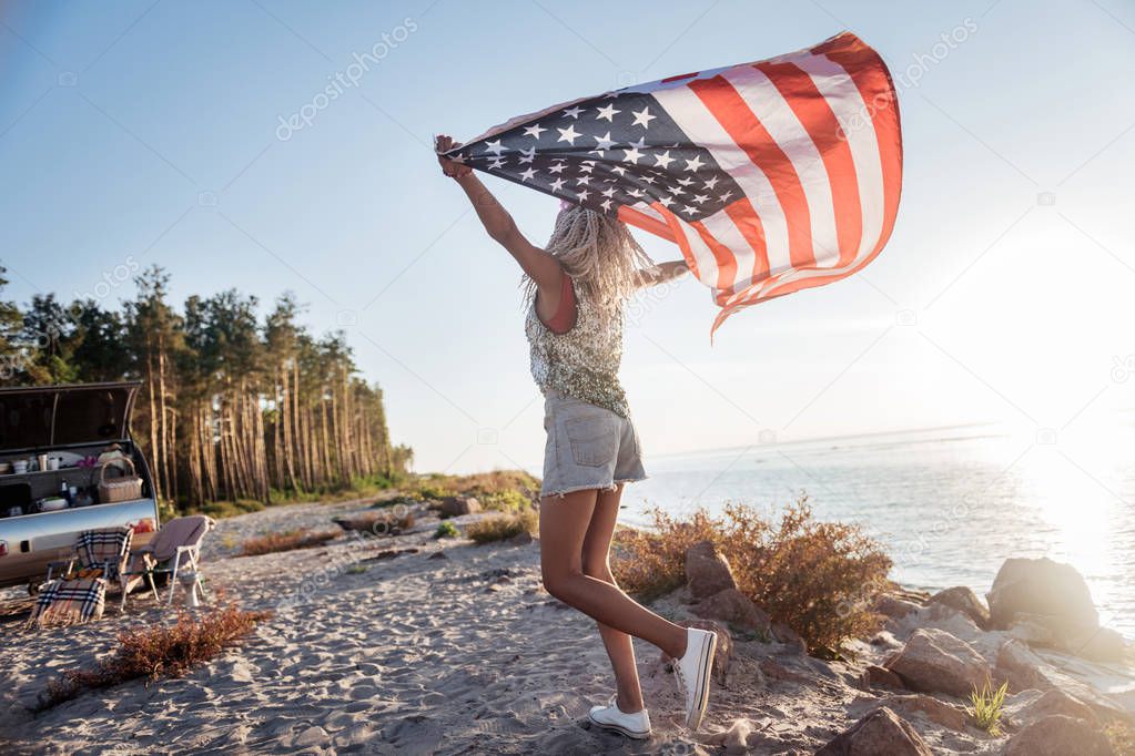 American patriotic woman traveling in compact trailer with her flag