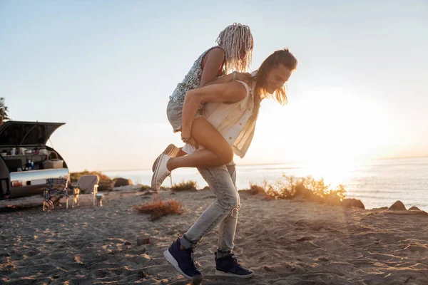 Сильный любящий мужчина несет свою девушку на руках, гуляя по пляжу — стоковое фото