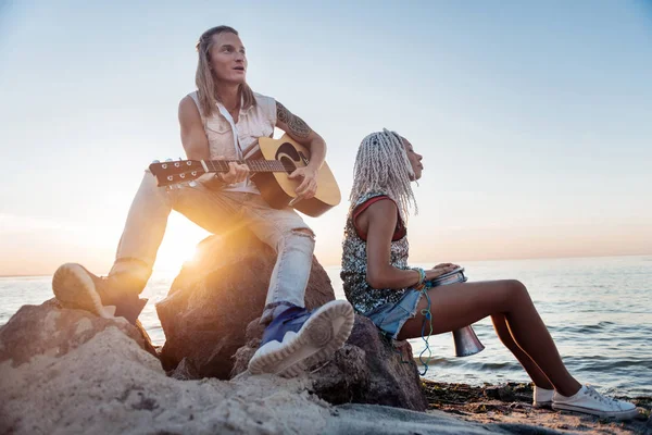 Blonde-haired man met tatoeage op hand gitaarspelen in de buurt van zijn vrouw — Stockfoto