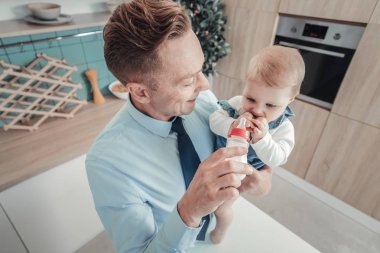 Dikkatli adam ayakta gülümseyen ve bir bebek beslenme.
