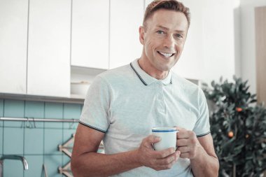 Gülümseyen ve bir fincan tutan hoş yakışıklı adam.