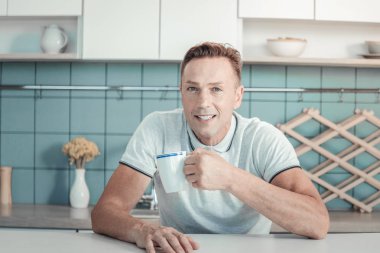 Oturma ve çay içme yakışıklı memnun adam.