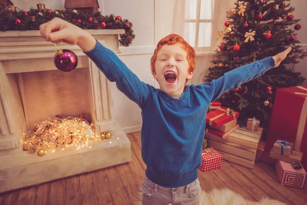 Joui roux garçon aux cheveux criant tout en tenant boule de Noël — Photo