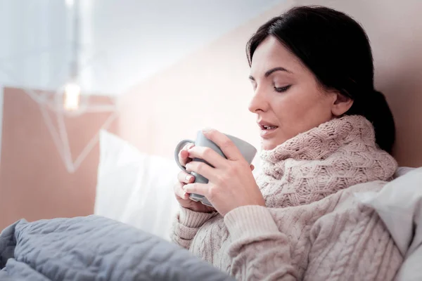 Pleasant woman with a cup of tea in the bed — Stock Photo, Image