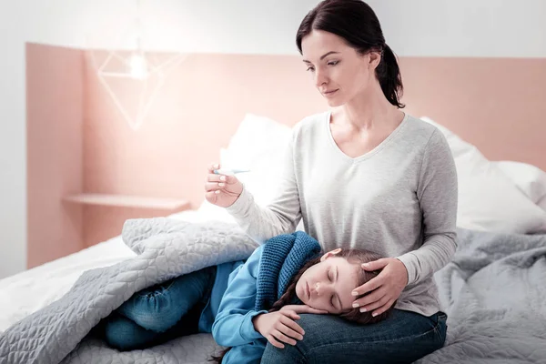 Портрет обеспокоенной матери с ребенком и термометром — стоковое фото