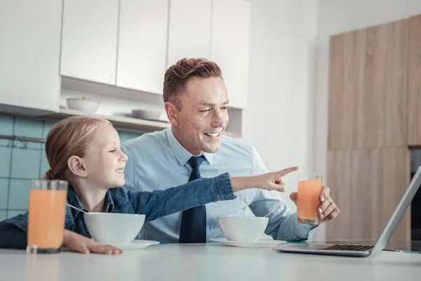 Aangename nieuwsgierig meisje wijzend op de laptop en glimlachen. — Stockfoto