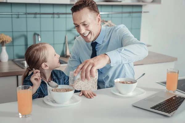 Caring handsome man smiling and feeding his daughter. — Stock Photo, Image