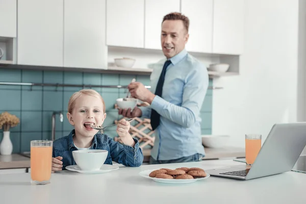 Satisfied little girl smiling and having breakfast. — Stock Photo, Image