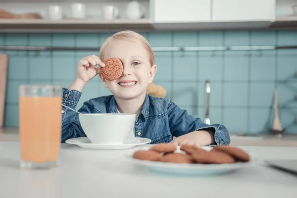 Смішна радісна дівчина посміхається і ховає око за печивом . — стокове фото