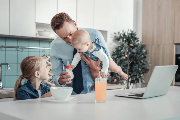 Schöner angenehmer Vater unterstützt Baby und hält eine Flasche in der Hand. — Stockfoto