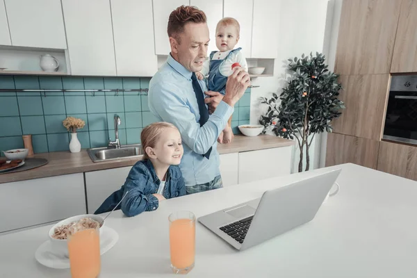 Optaget seriøs far holder en baby kigger på den bærbare computer . - Stock-foto