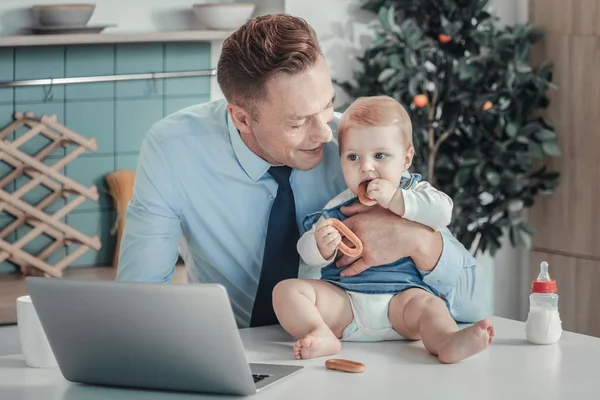 Satisfeito homem calmo sorrindo inclinando para um bebê . — Fotografia de Stock