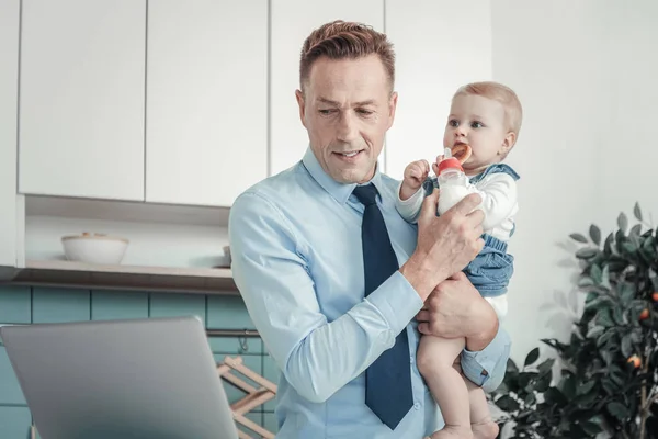 Obsazené zaměřený muž držící dítě být doma. — Stock fotografie