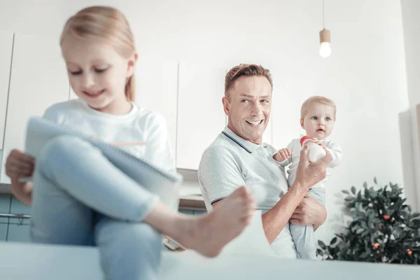 Satisfied pleasant father standing and holding a baby. — Stock Photo, Image