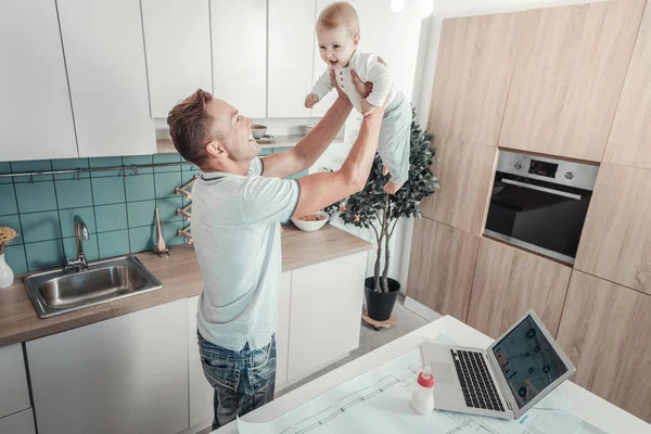 Satisfeito pai forte levantando um bebê e sorrindo . — Fotografia de Stock