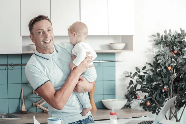 Fröhlicher gutaussehender Mann, der lächelt und ein Baby hält. — Stockfoto