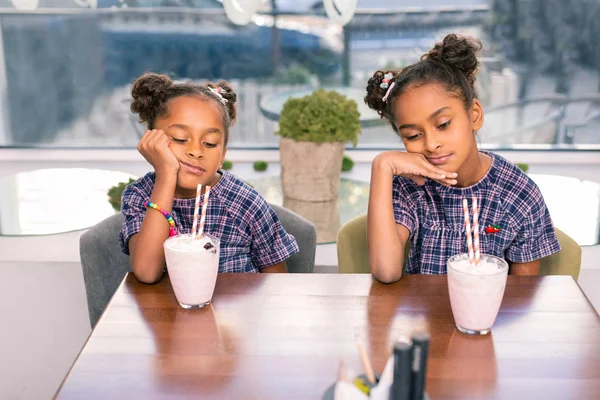 Dos lindos hermanos divertidos usando los mismos vestidos sintiéndose aburridos esperando comida —  Fotos de Stock