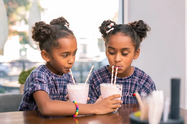 Lindas hermanas de buen corazón compartiendo sus cócteles de leche entre sí —  Fotos de Stock