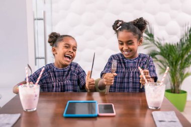 İki komik gülen kızı Gıda için beklerken çatal bıçak takımı tutan