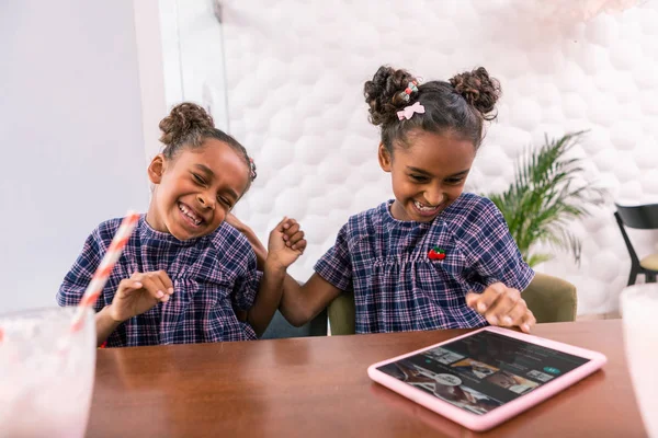 Lindas hijas sonrientes jugando trucos mientras desayunan en la cafetería — Foto de Stock