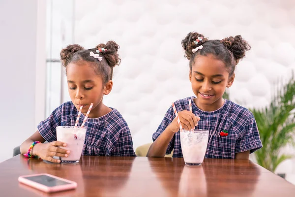 Dos hijas lindas bebiendo sus batidos después de ir de compras con los padres — Foto de Stock